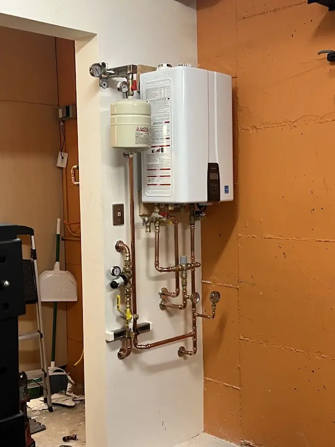 Plumbing technician inspecting water heater connections in Ashburnham